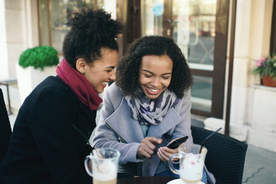Friends laughing smartphone city street