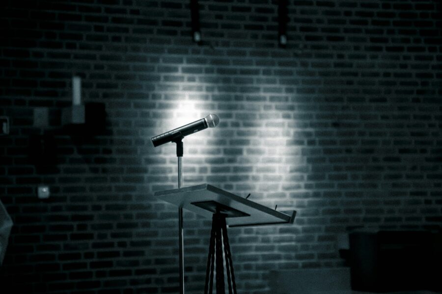 Comedian performing onstage brick wall microphone audience